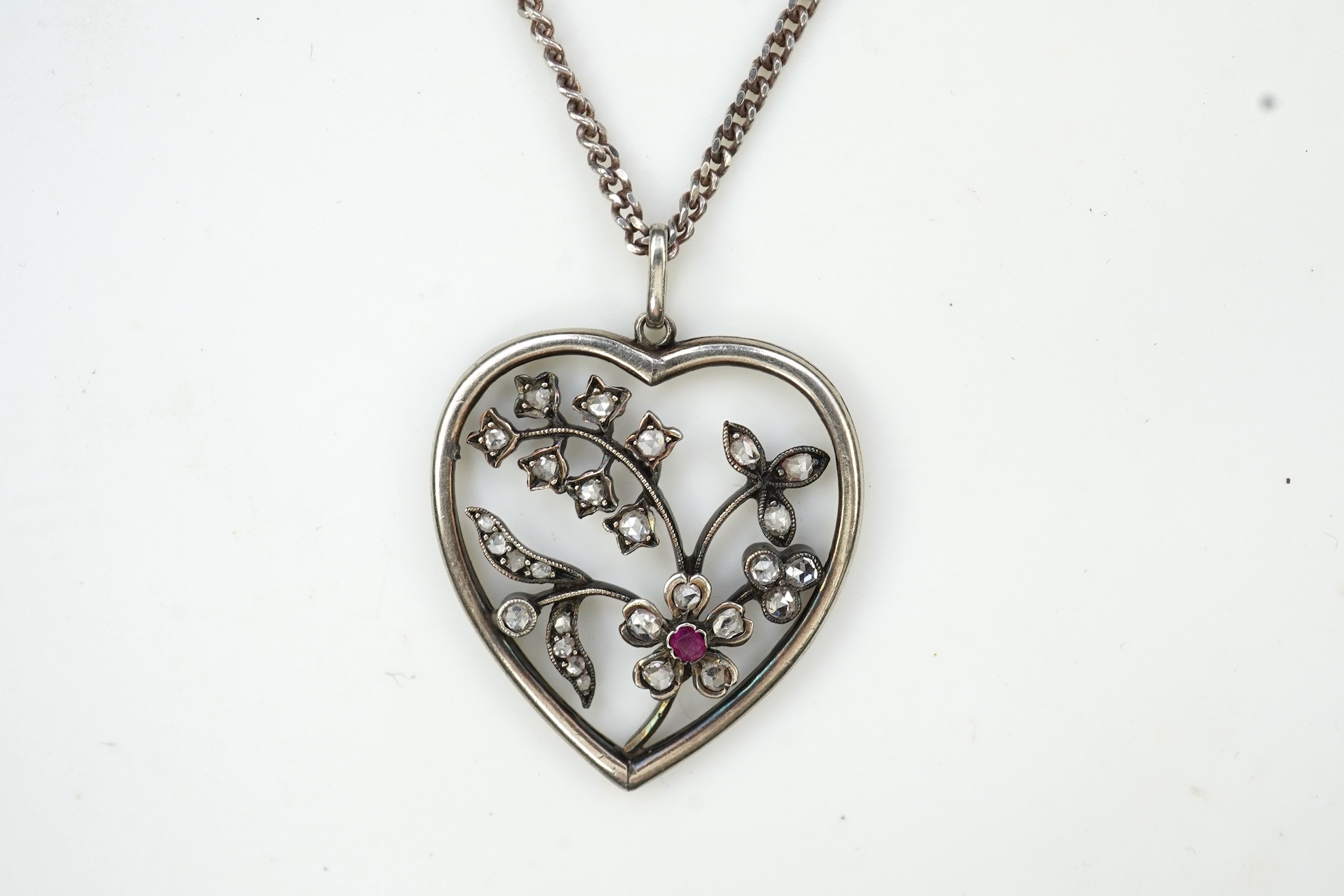 A diamond pendant, designed as a spray of flowers in a heart-shaped frame, set with rose-cut diamonds and a circular-cut ruby, to a later silver chain, pendant 3.1cm, chain length 44cm